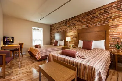 a hotel room with two beds and a brick wall at Hotel Abri du Voyageur in Montréal
