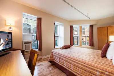 a bedroom with a bed and a tv and windows at Hotel Abri du Voyageur in Montréal