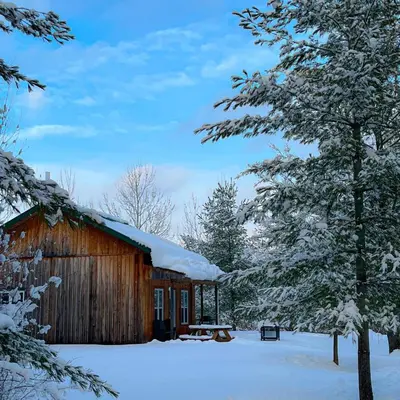 a wooden cabin in the snow with snow covered trees at Chalets du Domaine Yamaska in Bromont