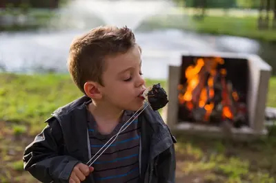 a young boy eating a piece of food with a stick at Chalets du Domaine Yamaska in Bromont