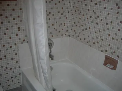 a white bath tub with a shower curtain in a bathroom at Hotel Motel Arnold in Woburn