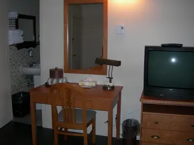 a room with a desk with a tv and a wooden table at Hotel Motel Arnold in Woburn