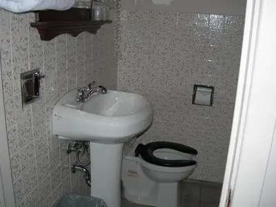 a bathroom with a sink and a toilet with a black seat at Hotel Motel Arnold in Woburn