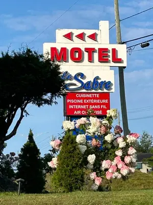 a sign for a motel with flowers in front of it at Motel le Sabre in Sherbrooke