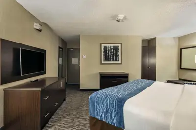 a hotel room with a bed and a flat screen tv at Comfort Inn Montreal Aeroport in Pointe-Claire