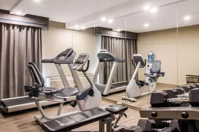 a gym with treadmills and ellipticals in front of a mirror at Comfort Inn Montreal Aeroport in Pointe-Claire