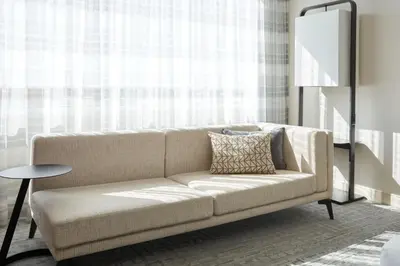 a couch in a living room with a window at Marriott Montreal Airport In-Terminal Hotel in Dorval