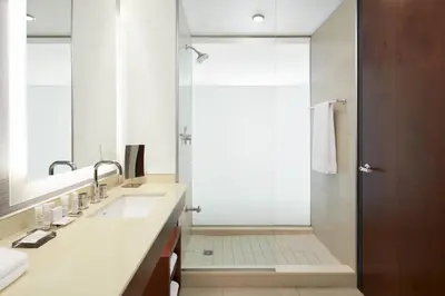 a bathroom with a shower with a glass door at Marriott Montreal Airport In-Terminal Hotel in Dorval
