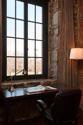 a desk with a lamp and a chair in front of a window at Auberge du Vieux Port by Gray Collection in Montréal