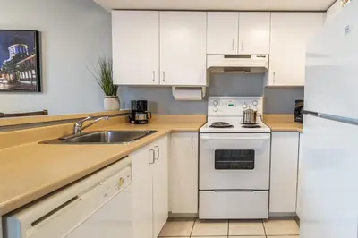 a kitchen with white cabinets and a sink at Hôtel Saint-Laurent Montréal in Montréal