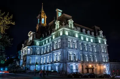 a lit up building with a clock tower at night at Holiday Inn Montreal Centre Ville Downtown by IHG in Montréal