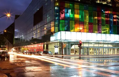 a building with colorful windows on a city street at night at Holiday Inn Montreal Centre Ville Downtown by IHG in Montréal