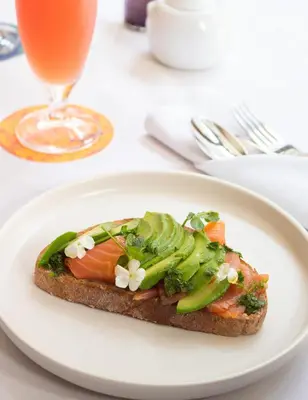 a white plate with a sandwich on a table with a drink at Hotel Gault in Montréal