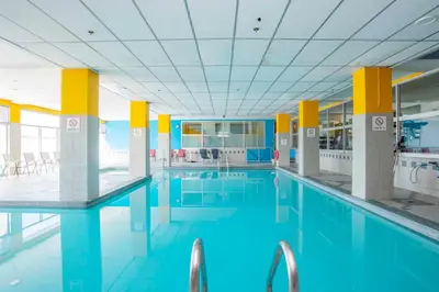 a large swimming pool with blue water in a building at Sandman Hotel Montreal - Longueuil in Longueuil