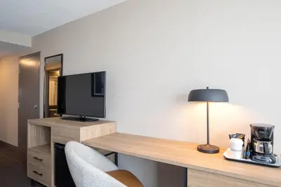 a room with a desk with a television and a lamp at Sandman Hotel Montreal - Longueuil in Longueuil