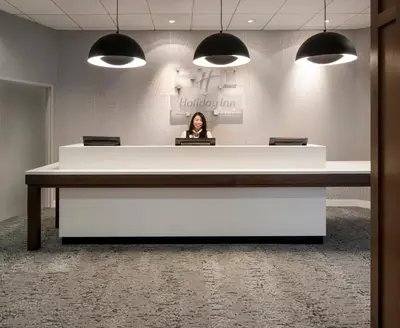 a woman is sitting at a large desk in an office at Holiday Inn Montreal Longueuil by IHG in Longueuil