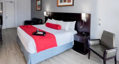 a bedroom with a bed with a red blanket and a chair at Auberge Royal Versailles in Montréal