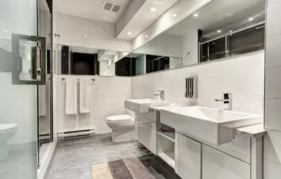 a white bathroom with two sinks and a toilet at Boutique Lofts Milton Parc by Simplissimmo in Montréal