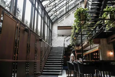 a woman sitting at a table in a building with stairs at William Gray by Gray Collection in Montréal
