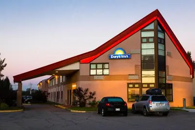 a dfw hotel with two cars parked in a parking lot at Days Inn by Wyndham Trois-Rivieres in Trois-Rivières