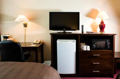 a hotel room with a television and a small refrigerator at Days Inn by Wyndham Trois-Rivieres in Trois-Rivières