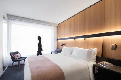 a bedroom with a bed and a chair and a window at Hotel Monville in Montréal