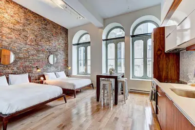 a bedroom with two beds and a brick wall at Le Merrill - Vieux Montréal in Montréal
