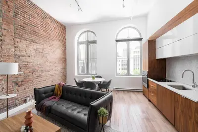 a living room with a black couch and a brick wall at Le Merrill - Vieux Montréal in Montréal