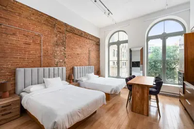 two beds in a room with a brick wall at Le Merrill - Vieux Montréal in Montréal