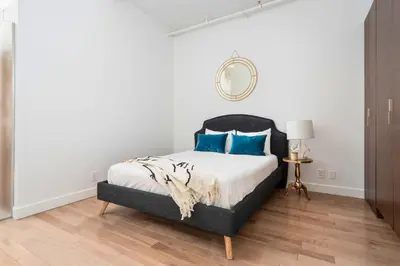 a bedroom with a bed with blue pillows and a mirror at Le Merrill - Vieux Montréal in Montréal