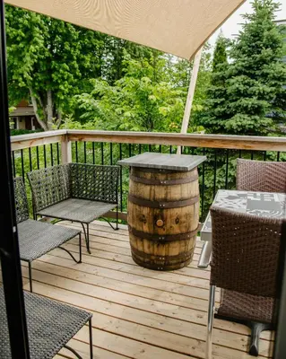 a wooden deck with a table and chairs and a barrel at Auberge Sutton Brouerie in Sutton