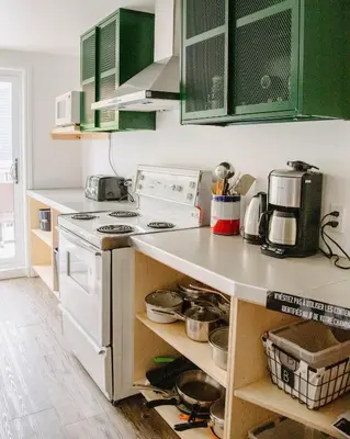 a kitchen with a white stove and green cabinets at Auberge Sutton Brouerie in Sutton