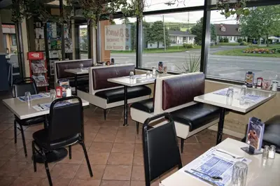 a restaurant with tables and chairs in front of a window at Motel Bellevue in Saint-Joseph-de-Beauce