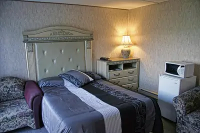 a bedroom with a bed and a tv and a couch at Motel Bellevue in Saint-Joseph-de-Beauce