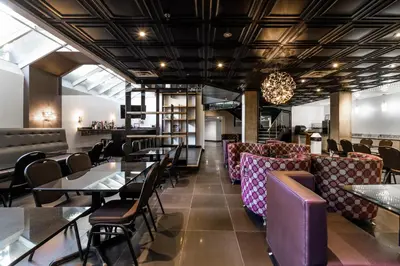 a restaurant with tables and chairs and a bar at Empire Suites in Montréal