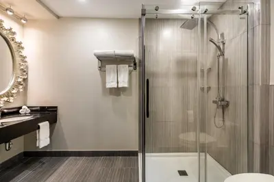 a bathroom with a glass shower and a sink at Empire Suites in Montréal