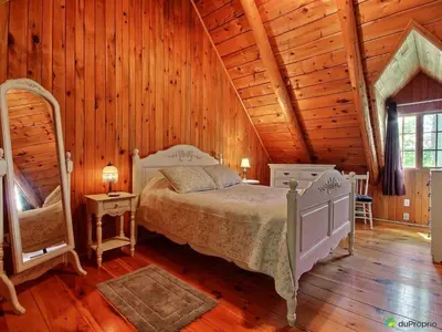 a bedroom with a bed in a wooden cabin at Aux Retrouvailles spa à l'année in Lac-Mégantic