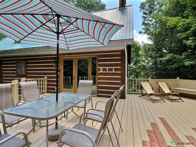 a patio with a table and chairs and an umbrella at Aux Retrouvailles spa à l'année in Lac-Mégantic