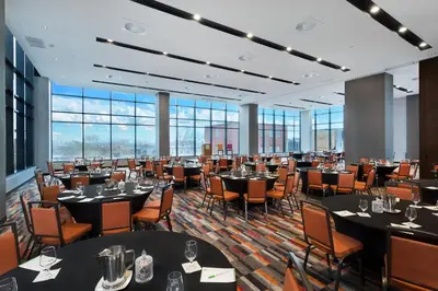 a dining room with tables and chairs and windows at Holiday Inn Hotel & Suites - Montreal Centre-ville Ouest by IHG in Montréal