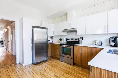 a kitchen with a stainless steel refrigerator and wooden floors at MTLVacationRentals -The Chic Laurier in Montréal