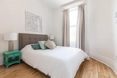 a white bedroom with a bed and a window at MTLVacationRentals -The Chic Laurier in Montréal
