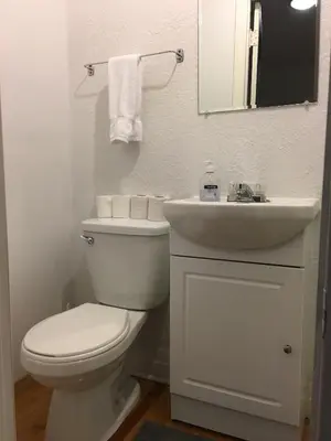 a white bathroom with a toilet and a sink at Hotel Mini Inc in Montréal
