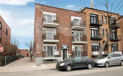 two cars parked in front of a brick building at Hotel Mini Inc in Montréal