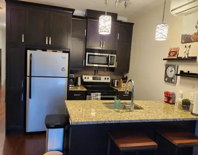 a kitchen with black cabinets and a white refrigerator at Le 204 Champlain Bromont in Bromont