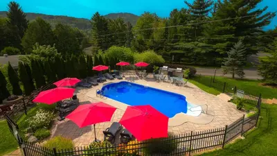 a patio with umbrellas and a pool with chairs at Le 204 Champlain Bromont in Bromont
