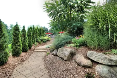 a path in a garden with plants and trees at Le 204 Champlain Bromont in Bromont