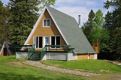 a small house with a gambrel roof and a porch at Chalet du barrage in East Broughton Station