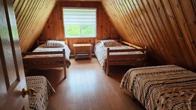 a attic room with three beds and a window at Chalet du barrage in East Broughton Station