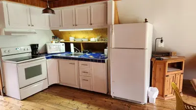 a kitchen with white appliances and a white refrigerator at Chalet du barrage in East Broughton Station