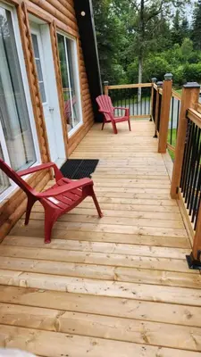 a wooden deck with two chairs on a house at Chalet du barrage in East Broughton Station